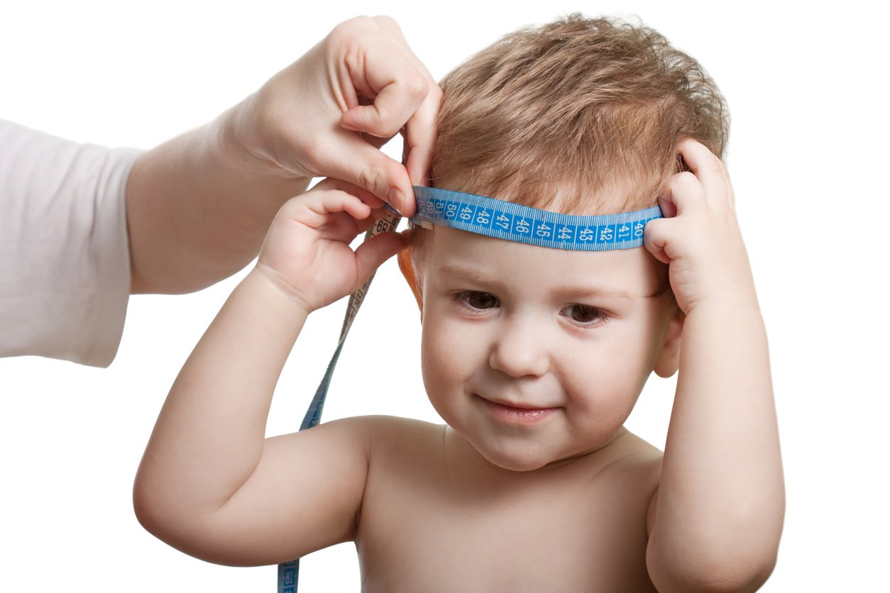 Barn som får huvudomfånget mätt med ett måttband.
