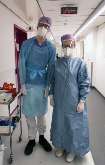 The picture shows two PhD students dressed in protective clothing before meeting COVID patients.