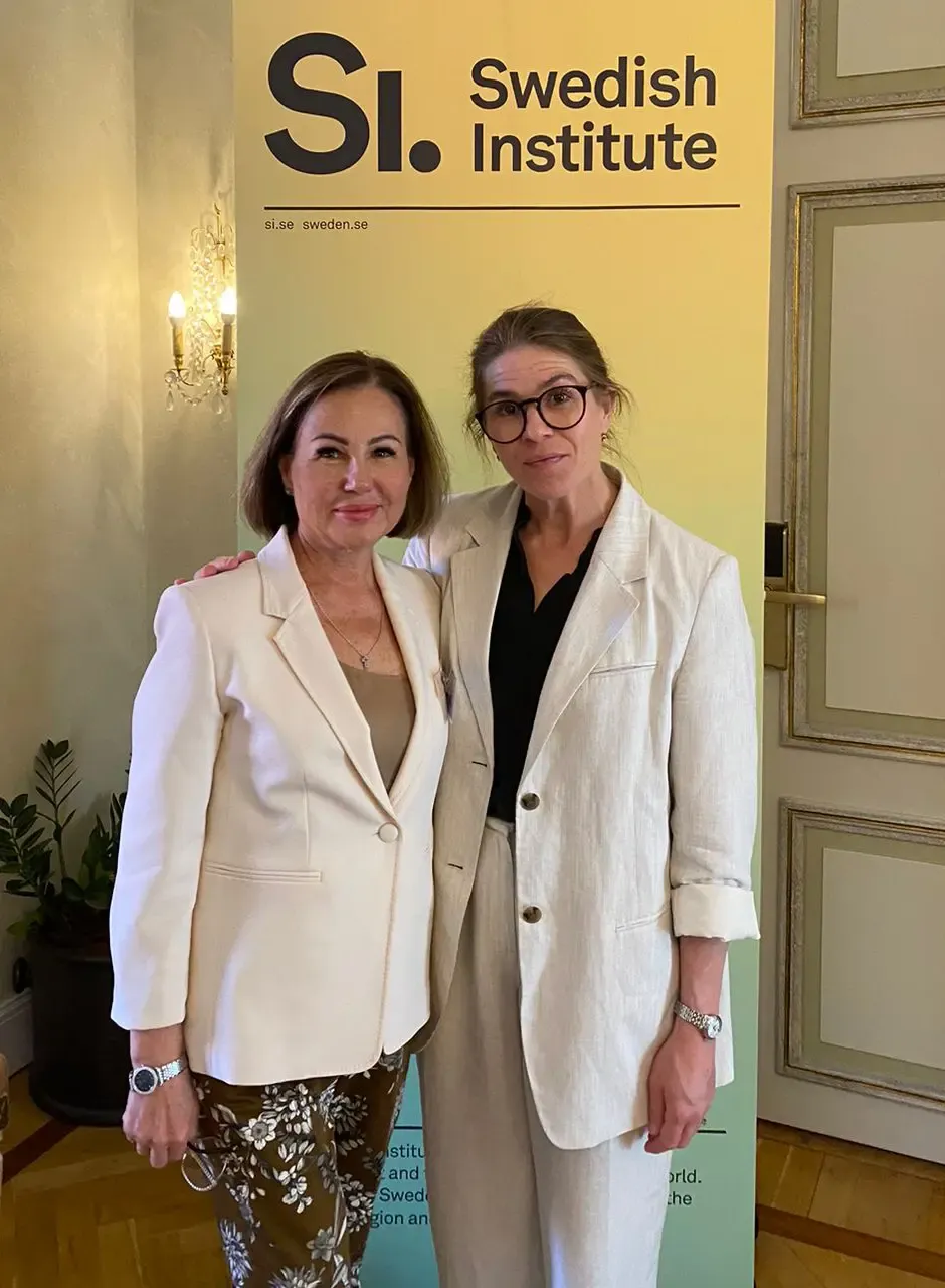 Two women are standing in front of a roll-up banner with the text 'Swedish Institute.