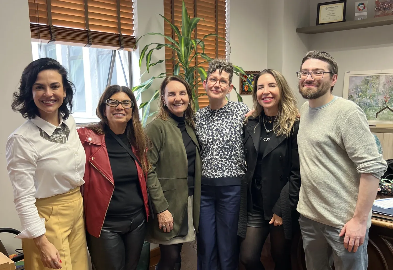 Six people standing together facing the camera in an office