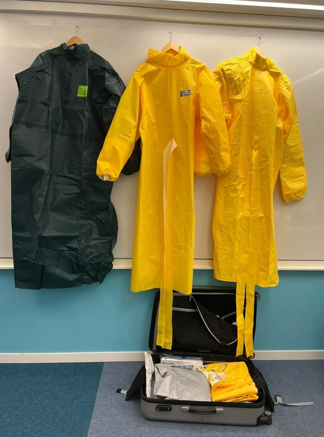 Three protective suits hanging on a wall