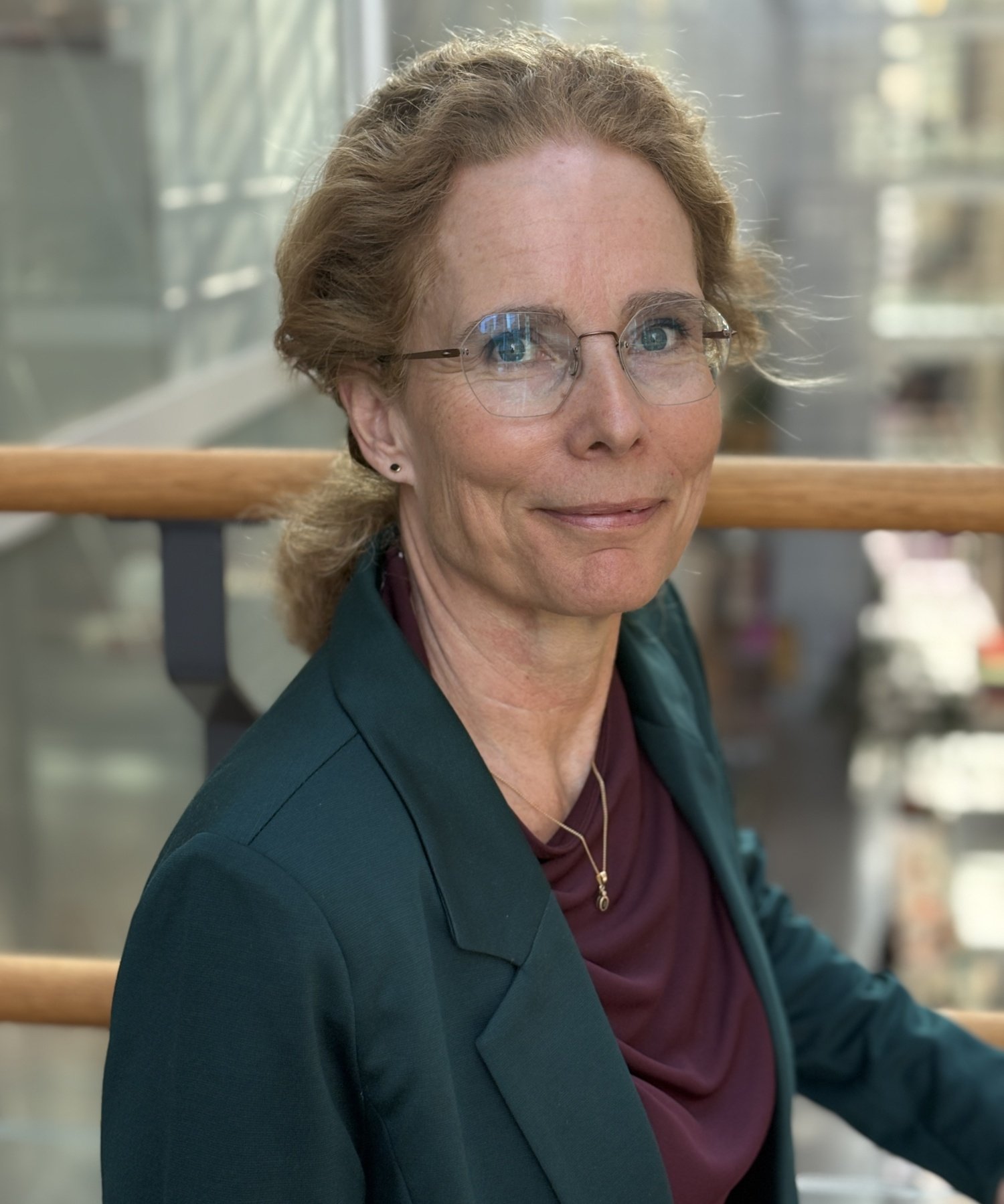 Portrait of woman in a green jacket and glasses.