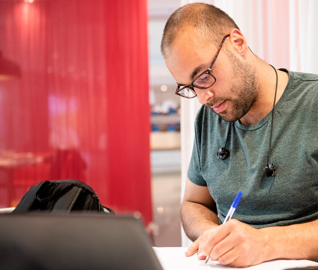 A person works at a desk with a pen and computer.