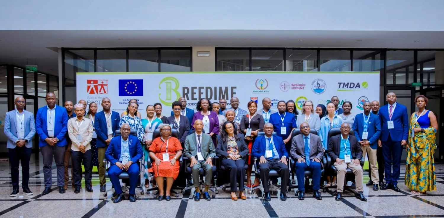 Fourty persons posing for a group photo, seven persons are sitting in from to the group. A sign with the text BREEDIME is behind the group.