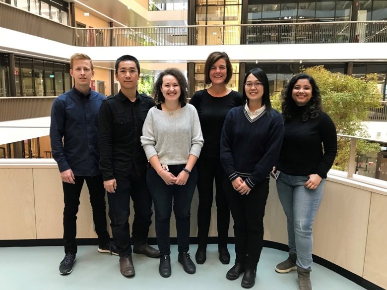 Group photo of six people standing in an atrium.