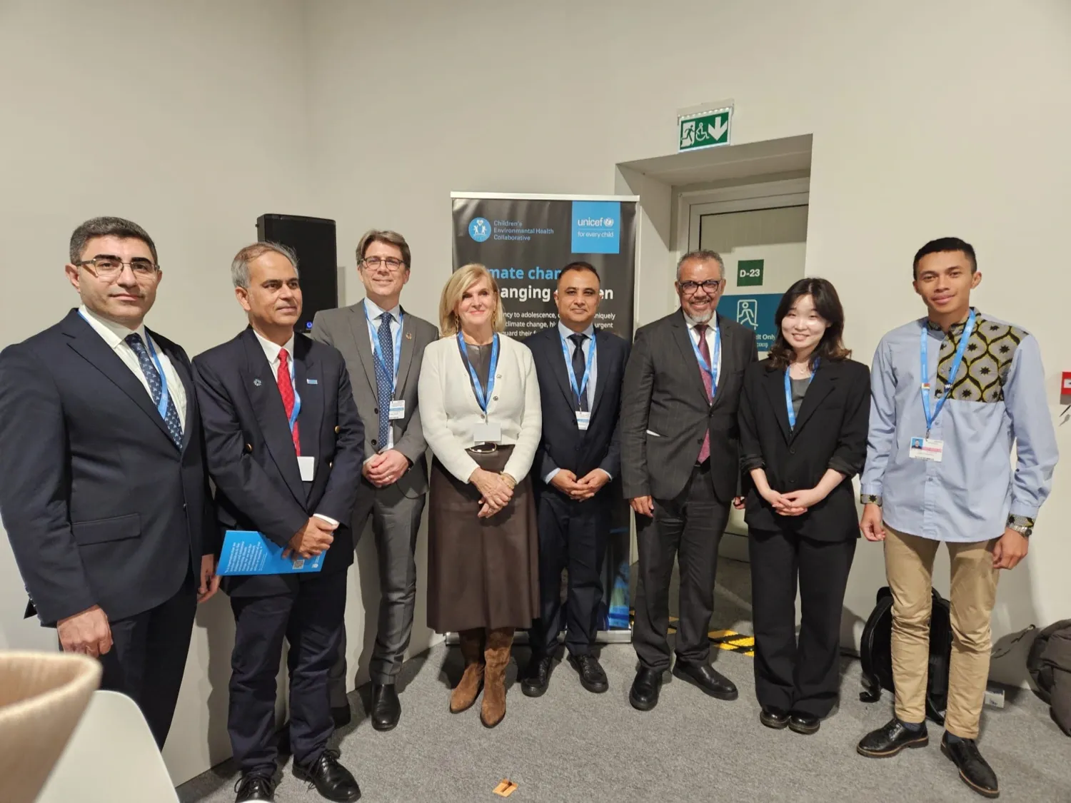 Six men and two women in a group photo in front of rollup with the UNICEF logo.