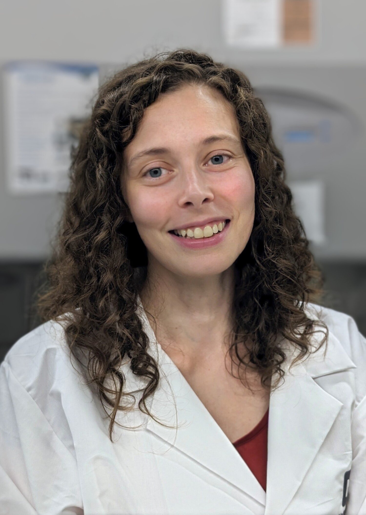 Portrait of a woman in lab coat with curly hair.