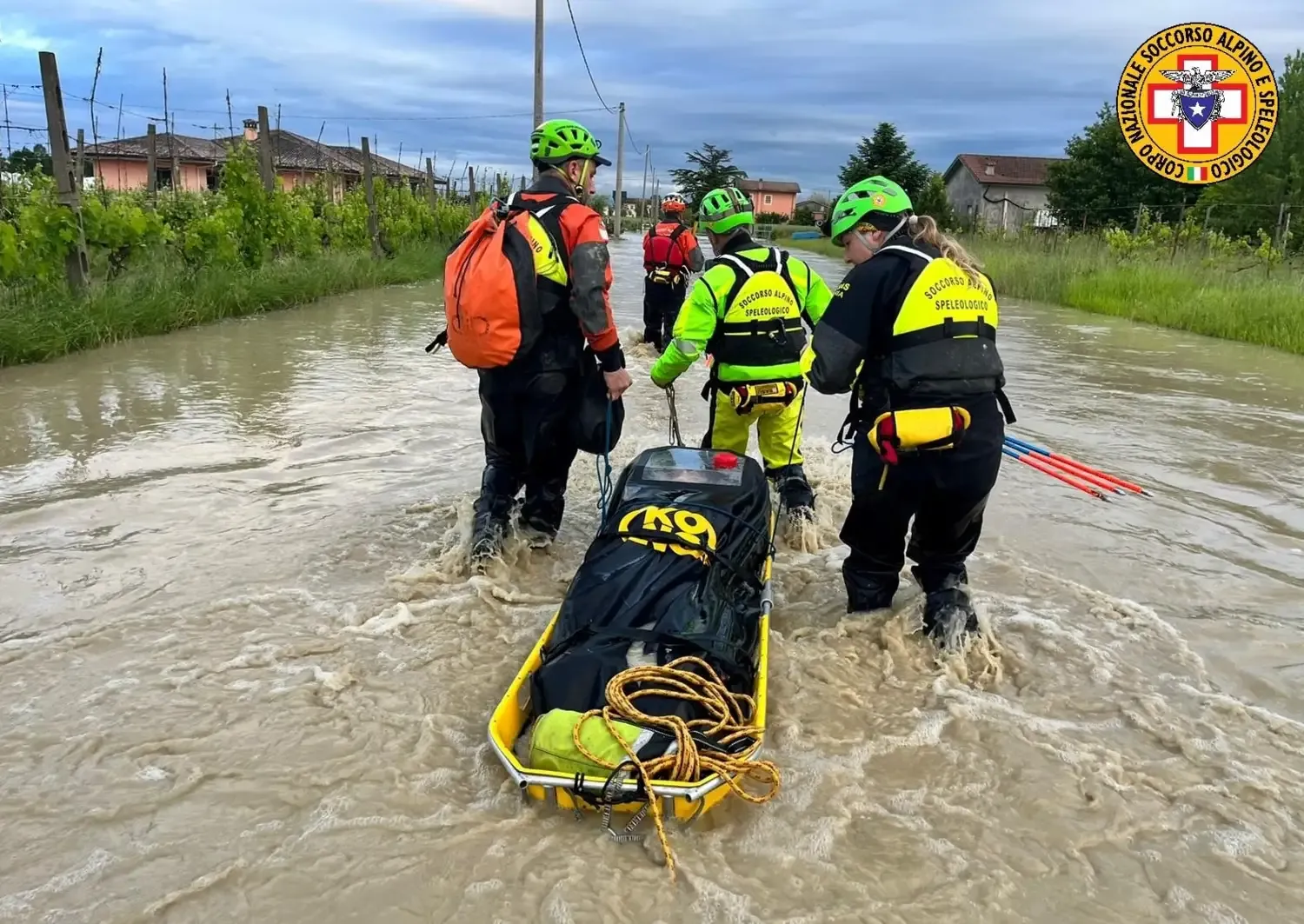 Three rescue workers drag a stretcher through a flooded street