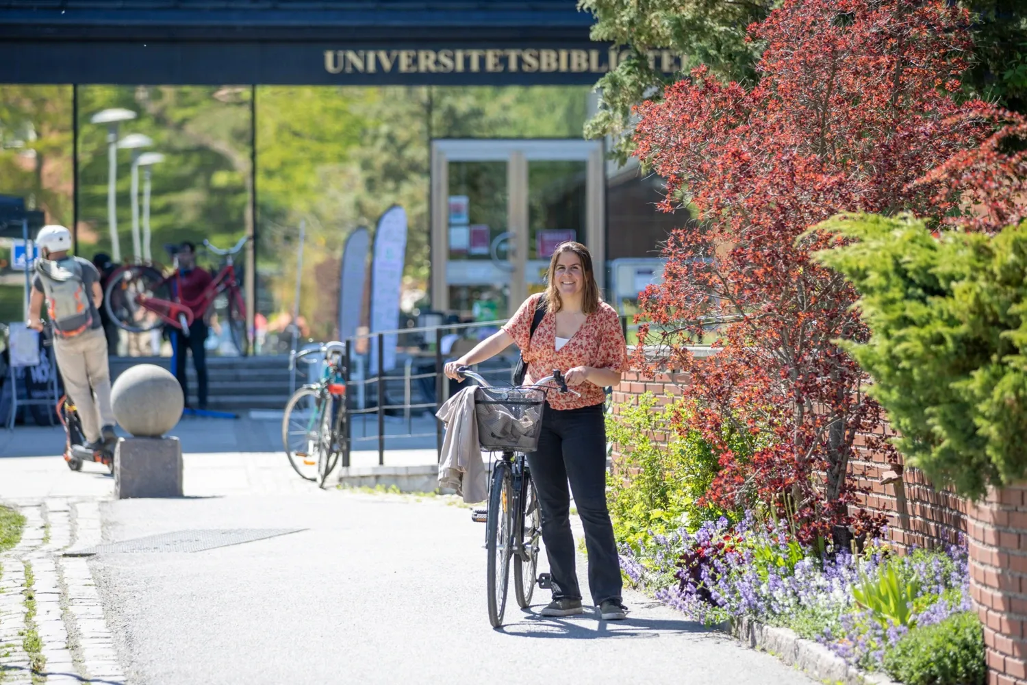 A woman standing next to her bike in a fall scenery.