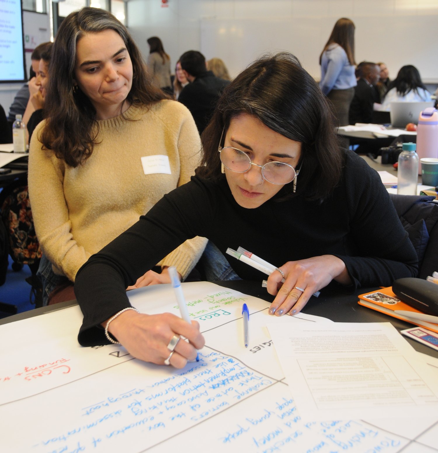 Two people are leaning over a table, working on a group project at the conference.
