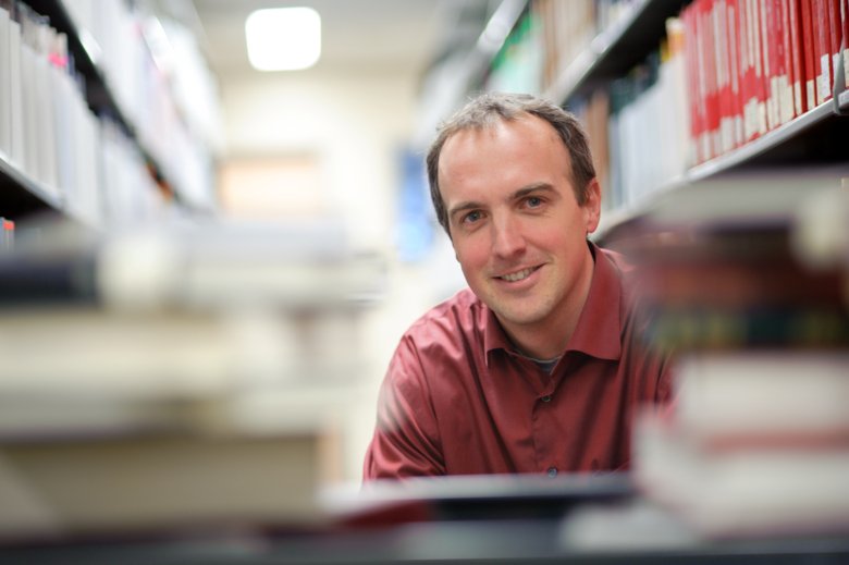 Professor Kevin Eva sitting behind a pile of books.