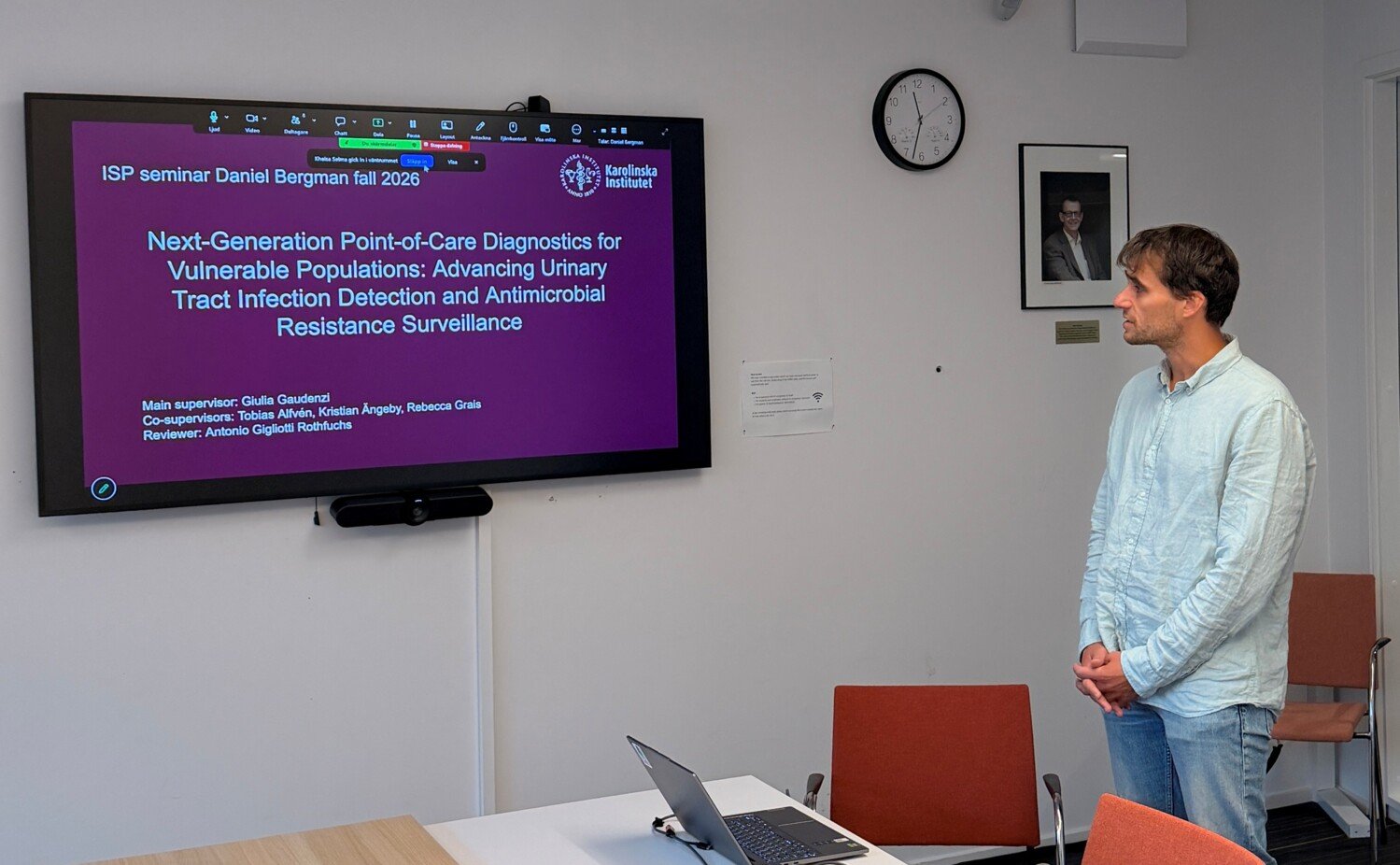 Daniel Bergman standing in a seminar room next to a screen showing the title of his seminar.