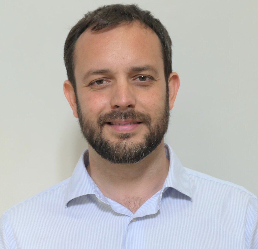 Portrait picture of Davide in light blue shirt against a light background.