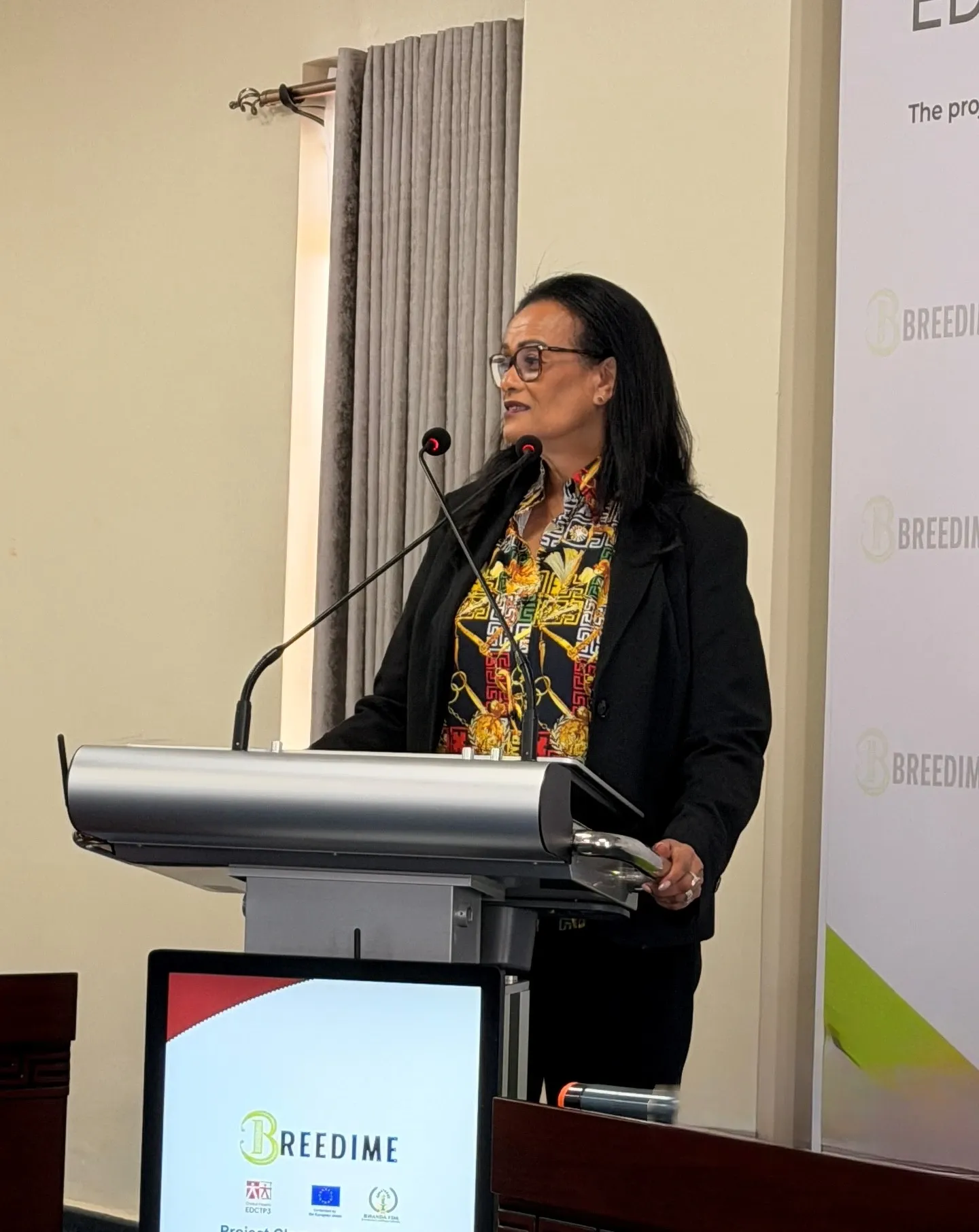 Eleni Aklillu stands behind a podium with the text BREEDIME project closure symposium.