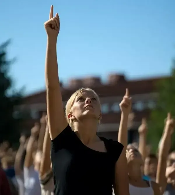 Students in a schoolyard reaching a hand toward the sky.