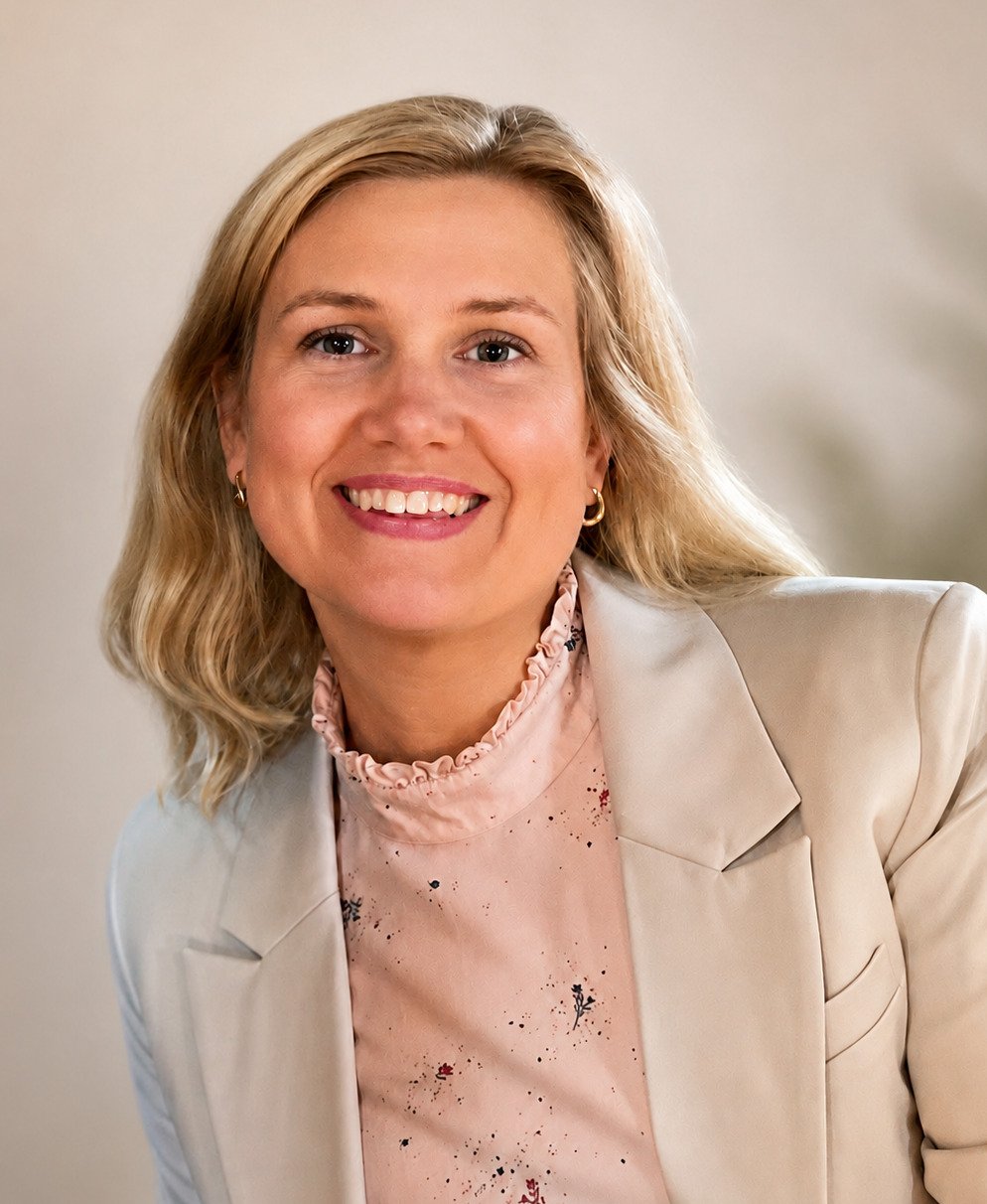 Portrait of a blonde woman wearing a beige blazer.