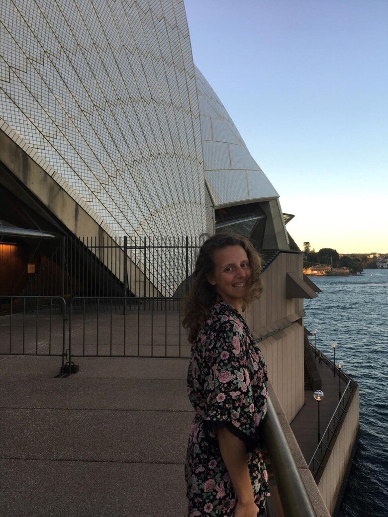 Image of a female student standning by the waterfront looking happy.