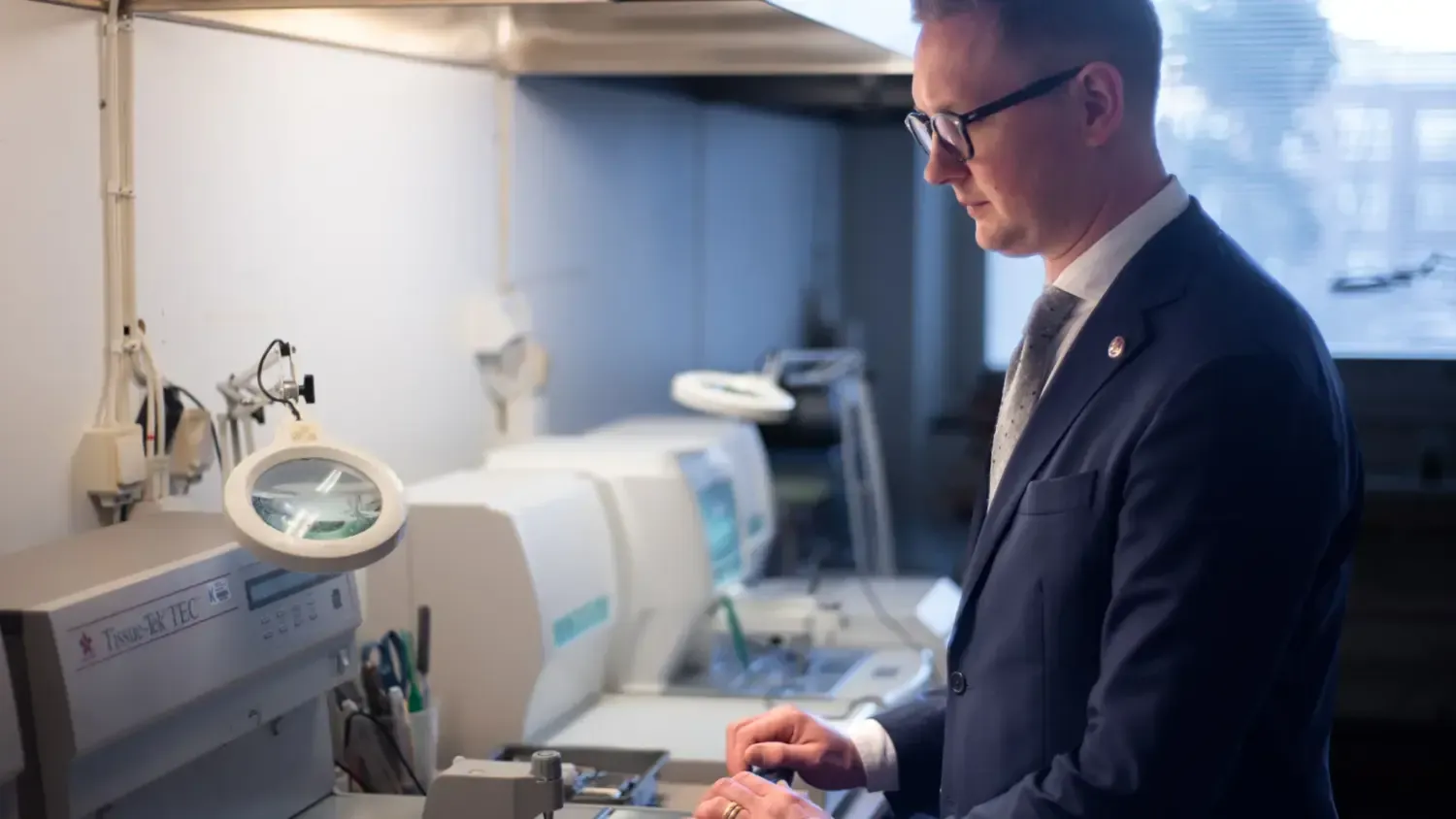 An image of a man wearing a suit, standing in a lab.
