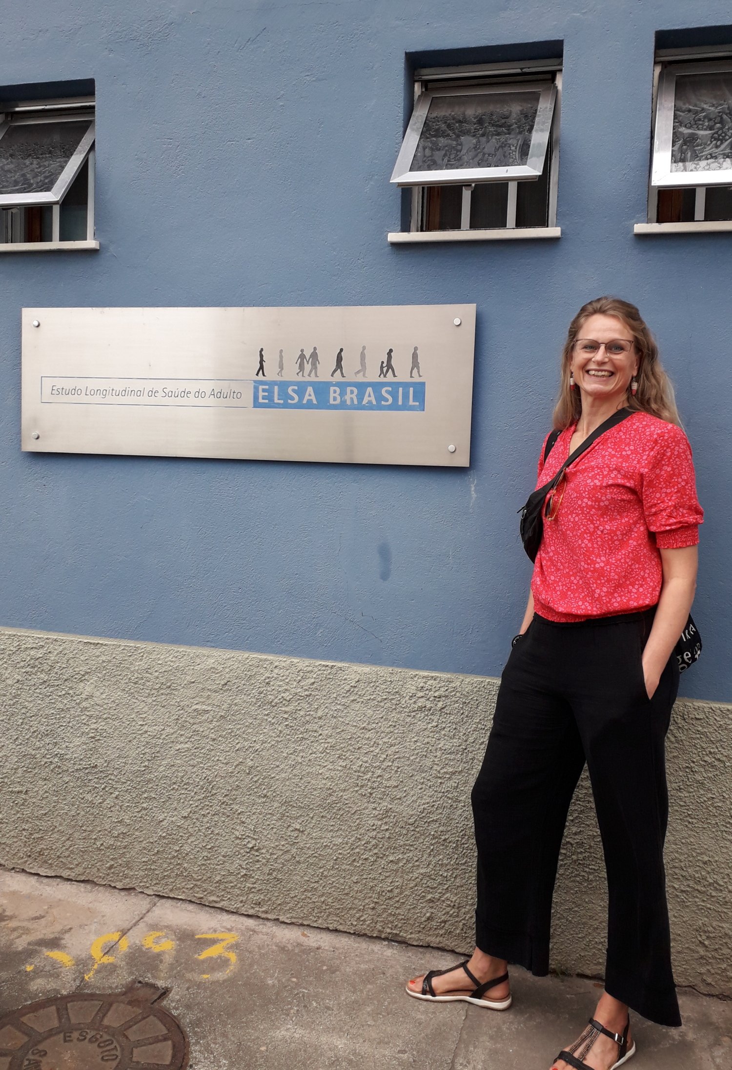 Pernilla is leaning against a blue wall next to a sign.