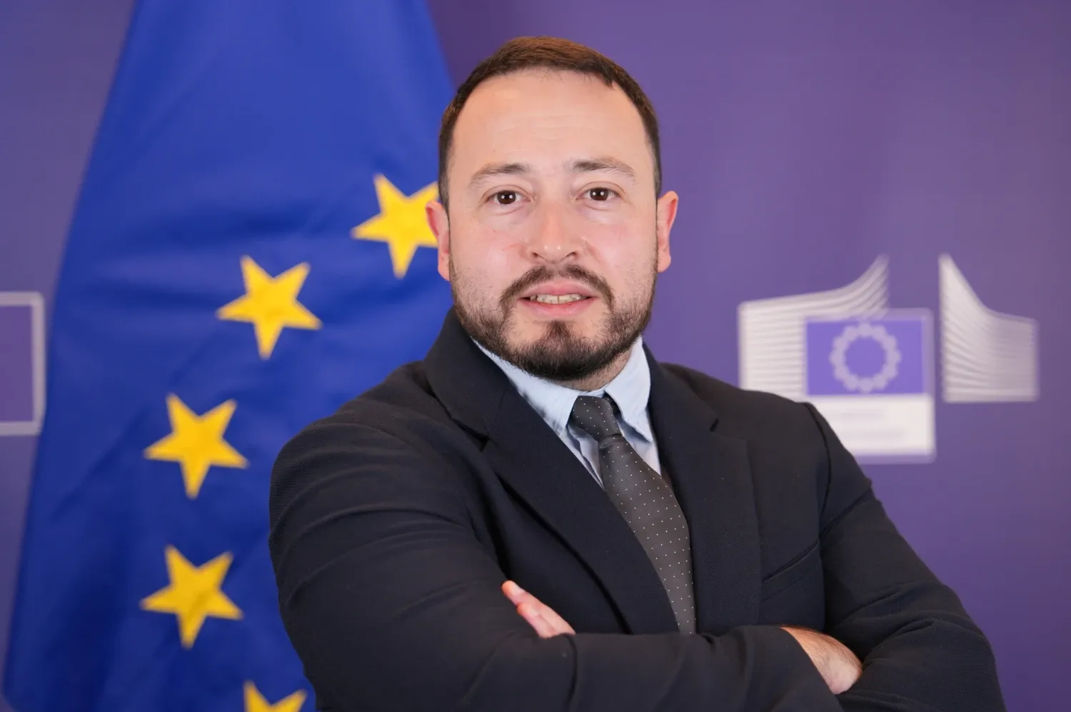 Profile picture of a man with short dark hair and a beard wearing a dark suit