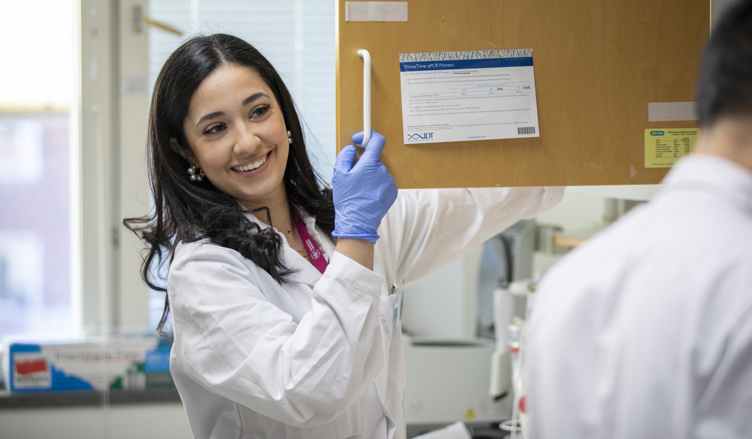 Woman in lab smiling and talking to another researcher.