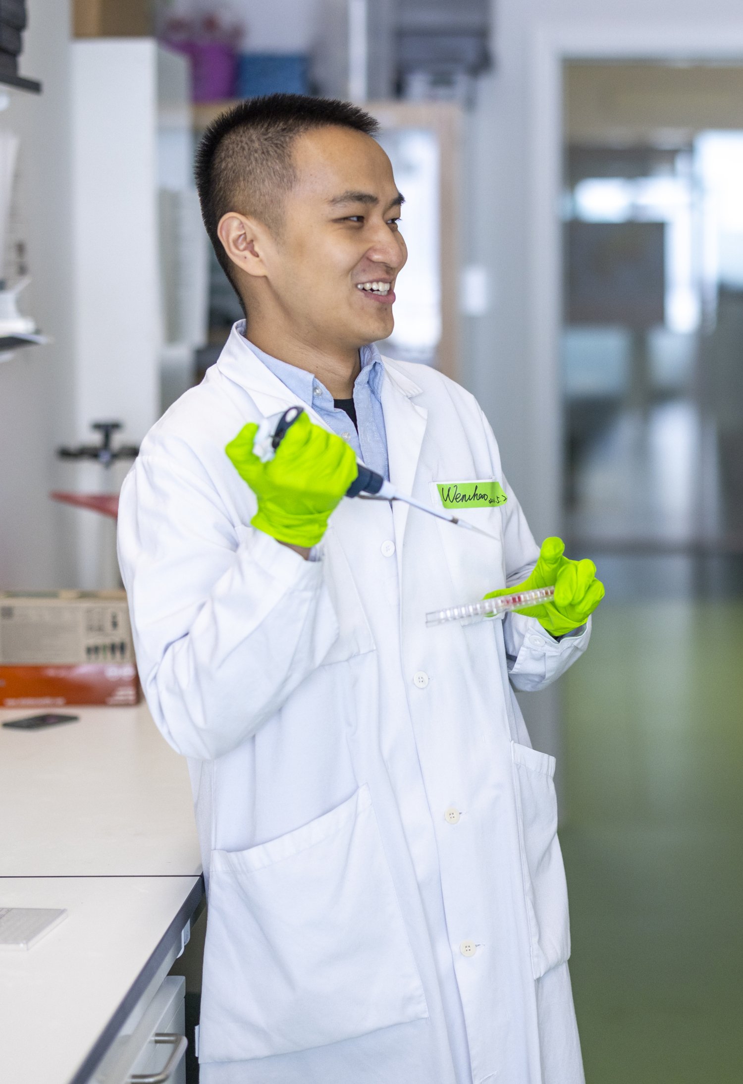 Man and woman standing in lab environment talking. The man is holding a pipette.