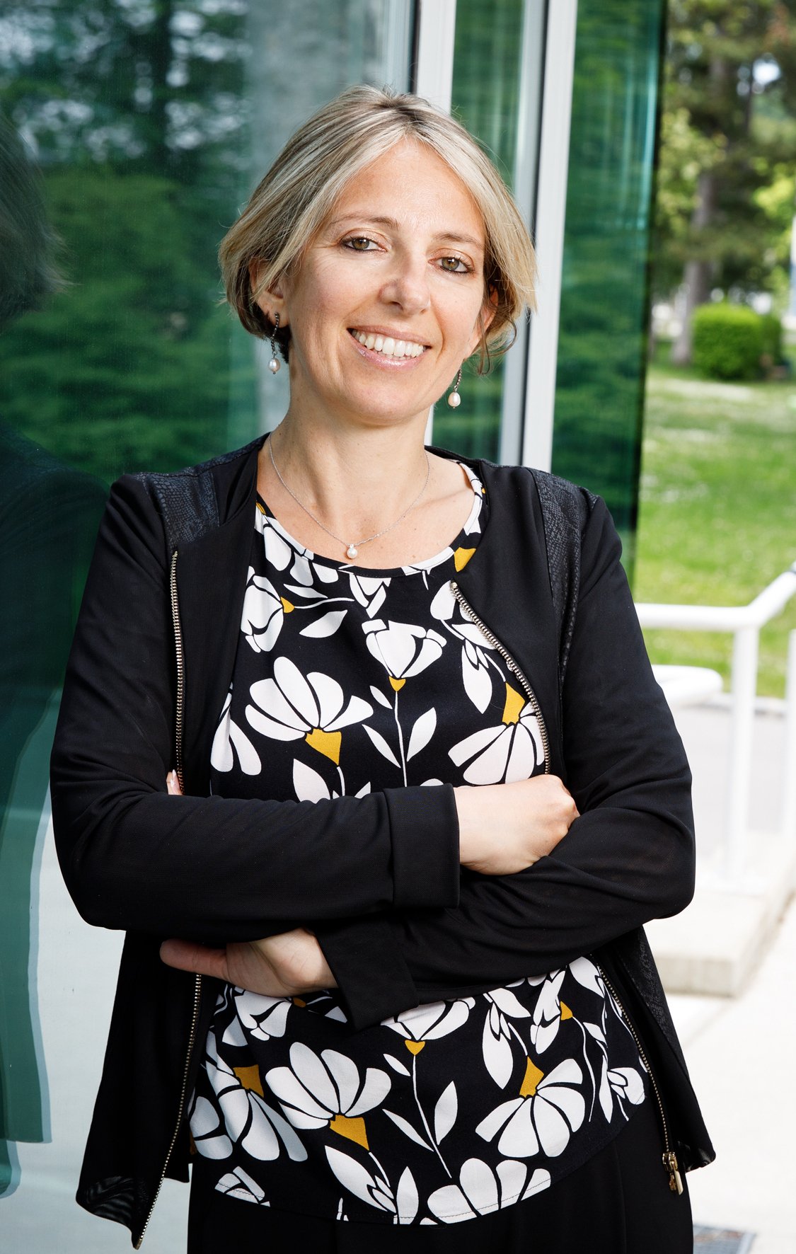 A portrait of a woman leaning agains a glass wall.