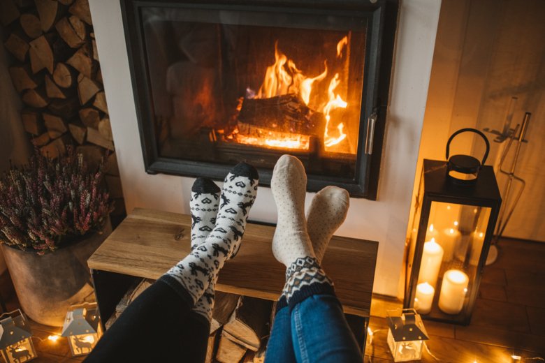 Two pair of stockinged feet by a cozy fire place.