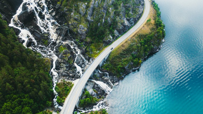 Drone panoramic photo of the car driving through picturesque road above the huge waterfall near the fjord in South Norway.