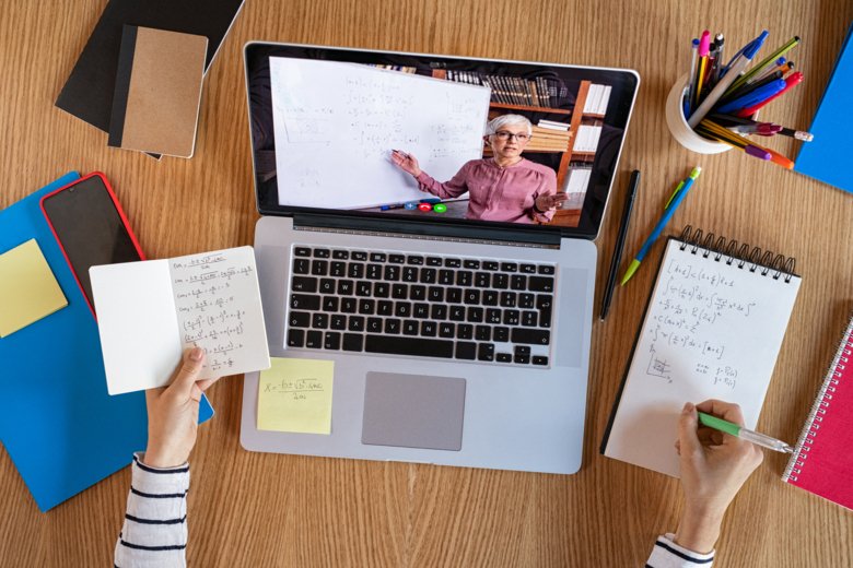 Laptop with online meeting on a table with note pads.