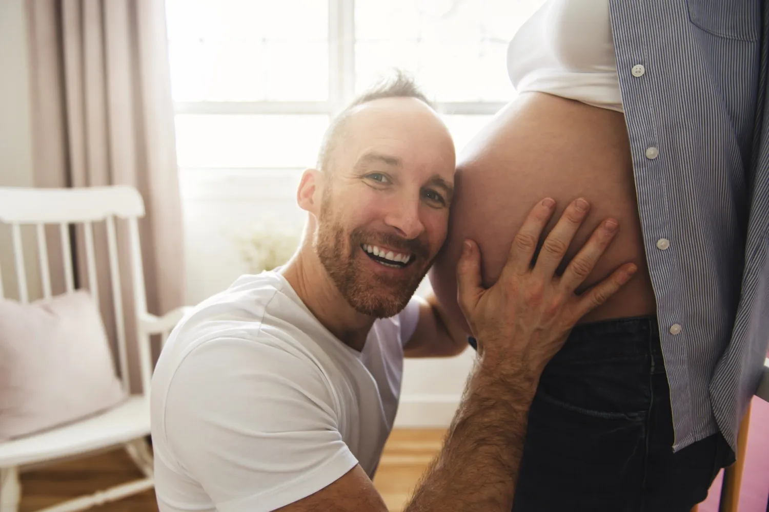 A man with his face at a pregnant belly