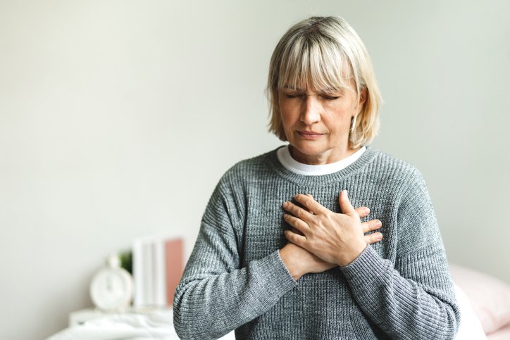 Woman with chest pain sitting on a bed