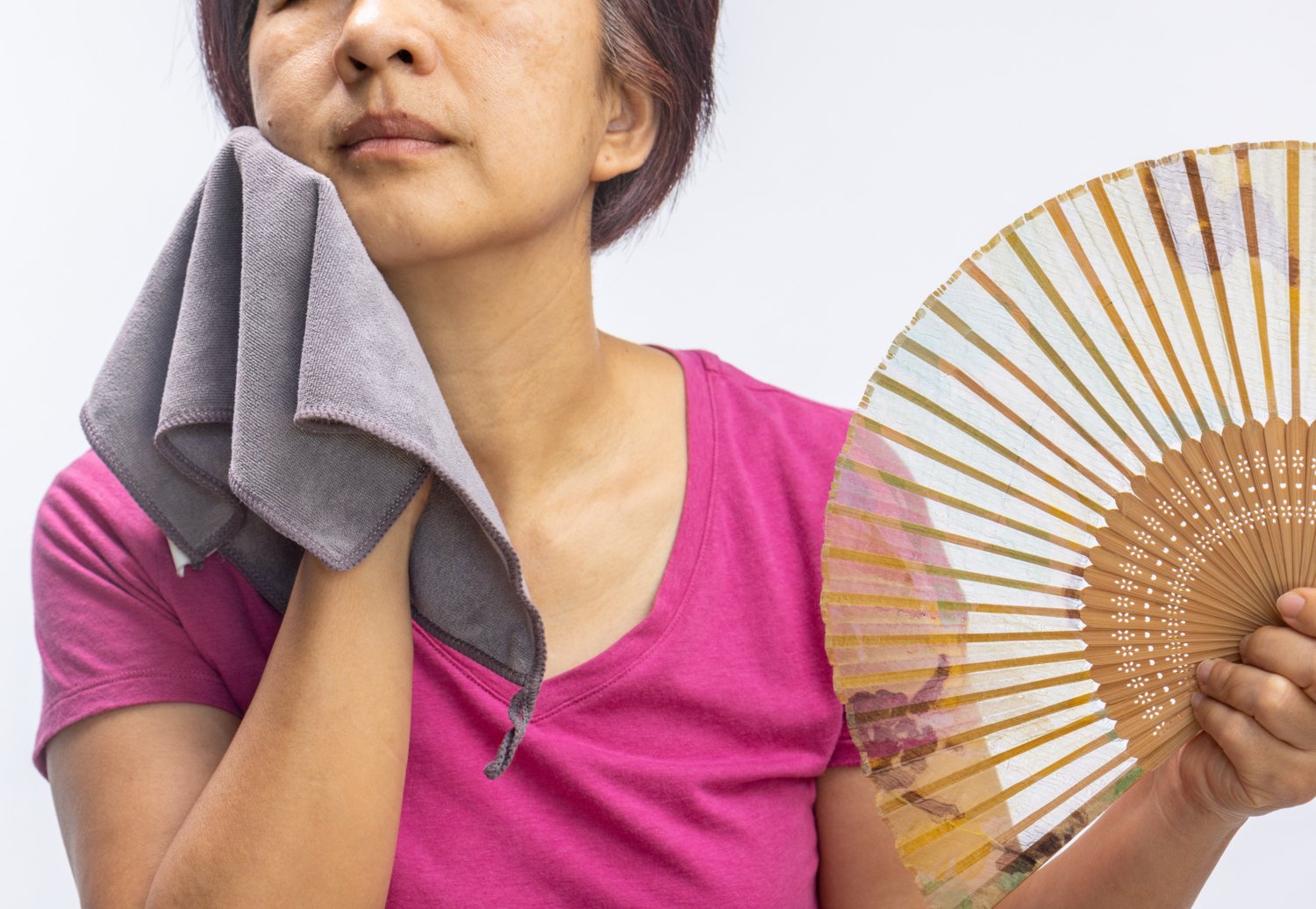 Woman cools down with fan and towel.