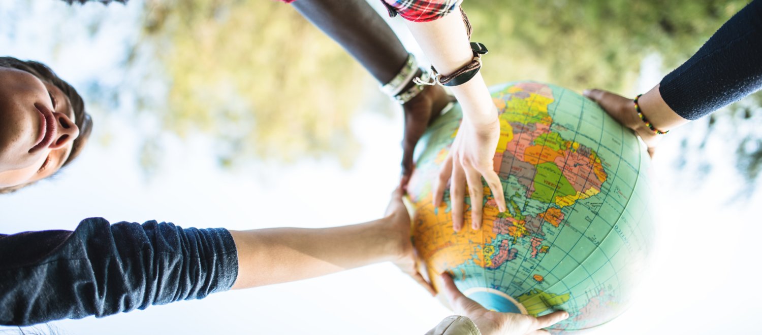 A group of students together holding up a miniature globe.