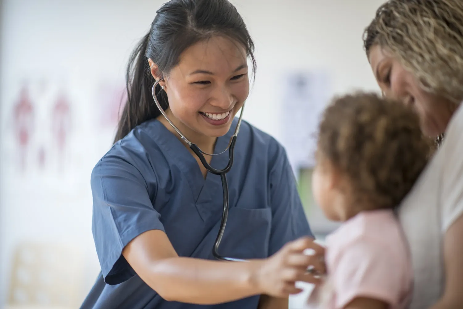 A nurse is listening to a little girl's heart with a stetoscope.