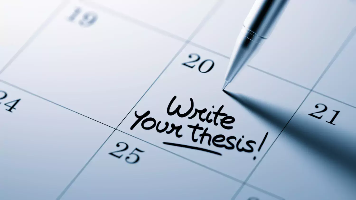 note in a desk calendar that says "write your thesis" on it