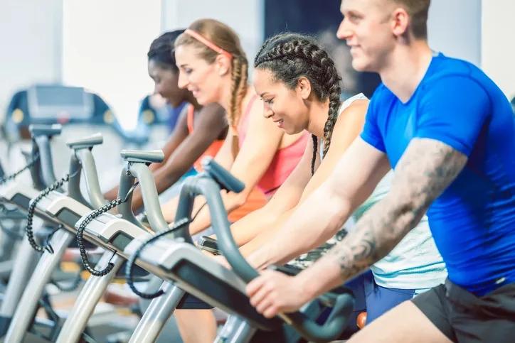 Stock photo showing a group of people exercising on bikes in a gym.