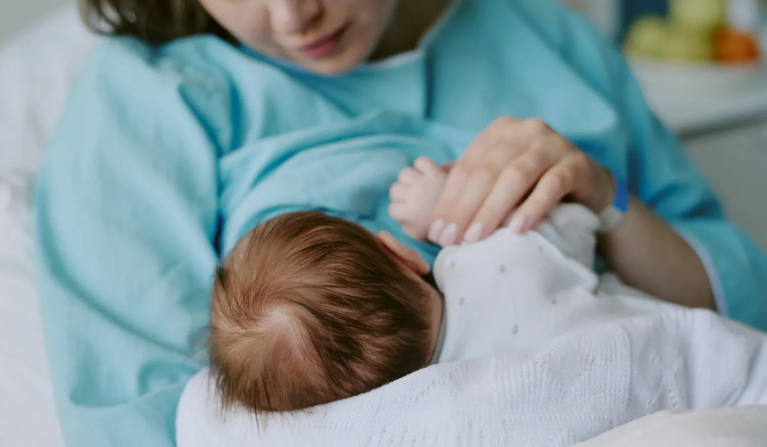 A woman is holding a swaddled newborn baby in her arms.