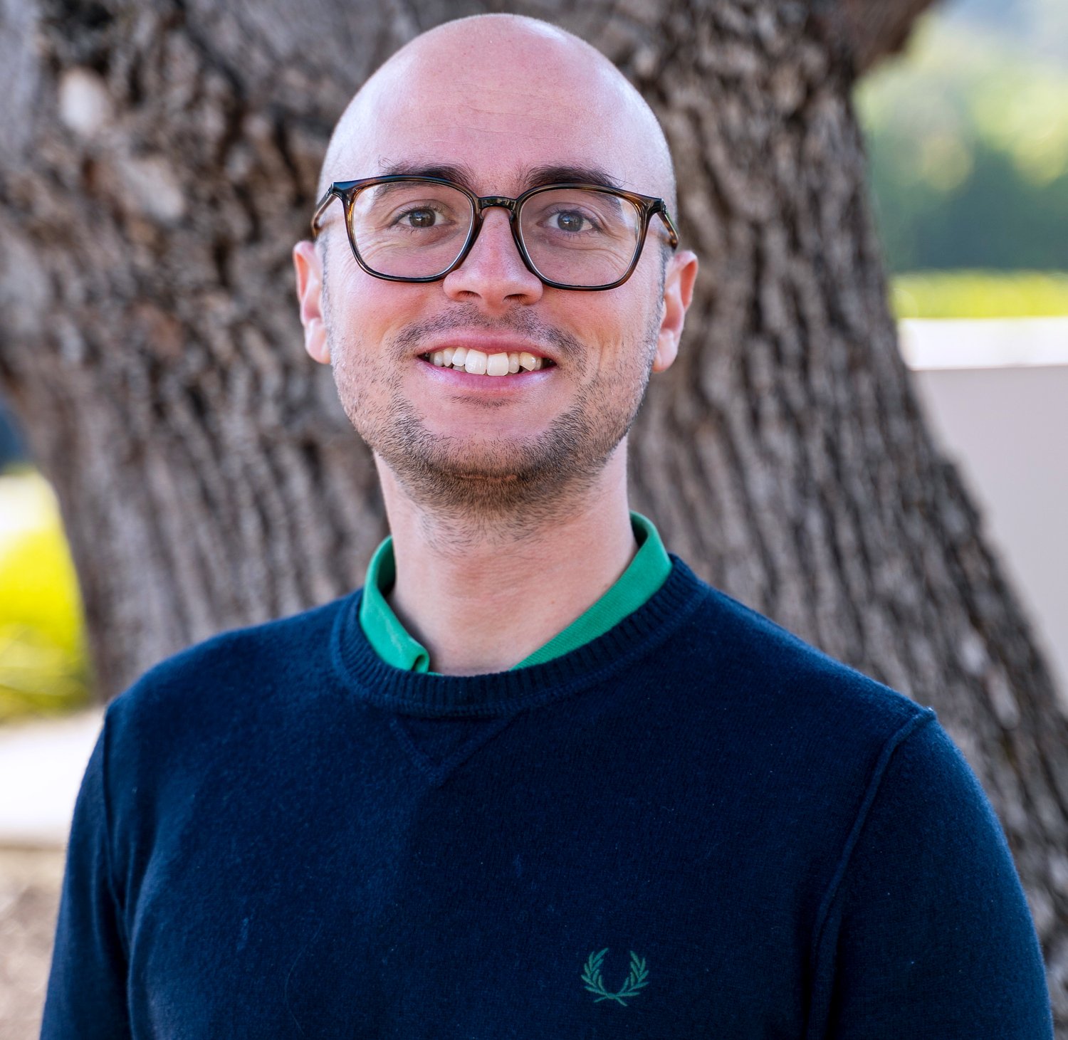 Portrait in front of a tree trunk.