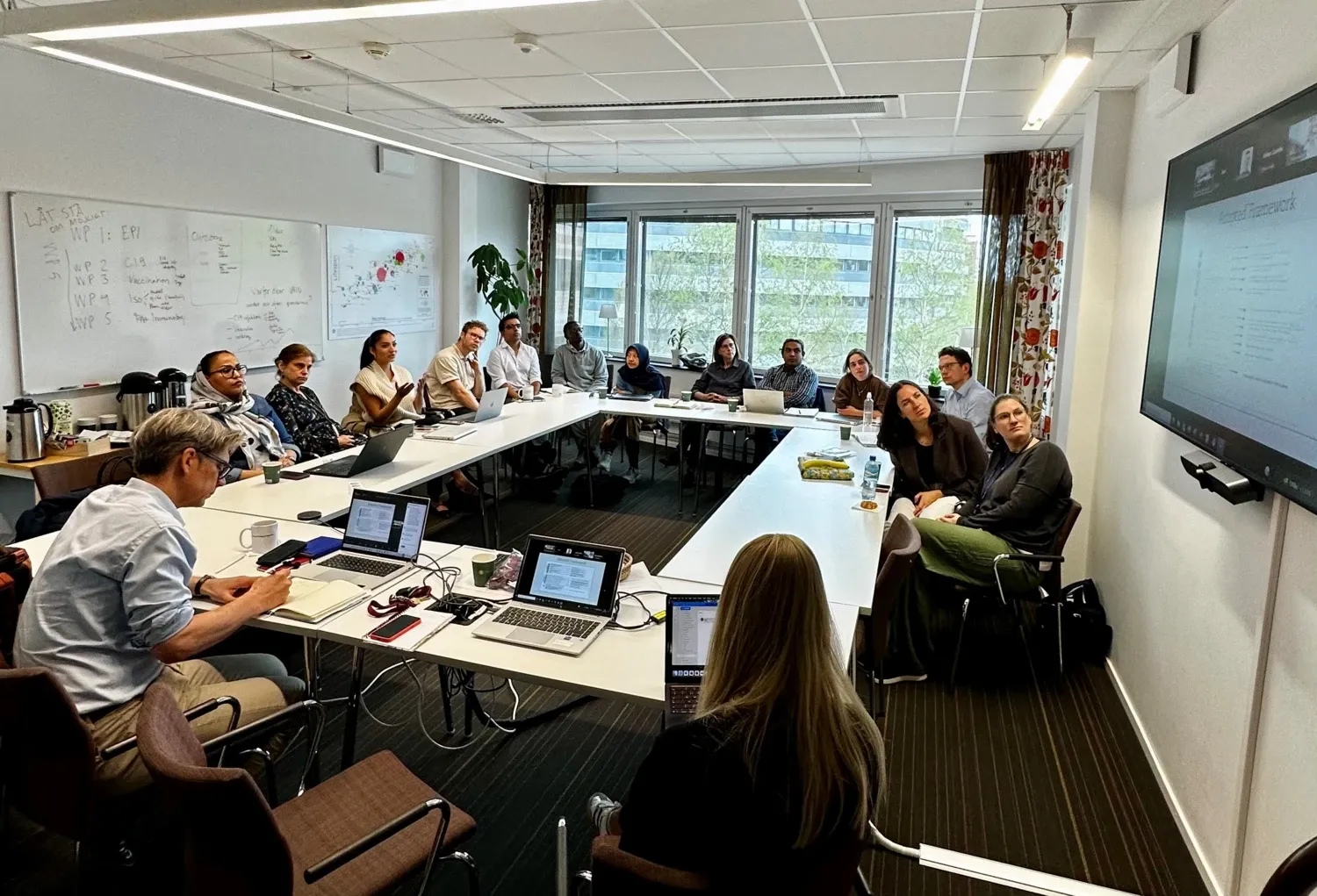 Group of people in a meeting, listening to a speaker.