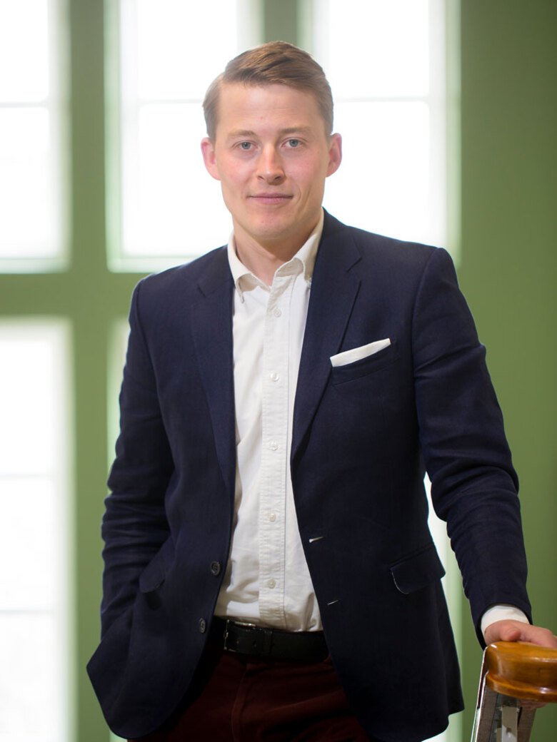 Portrait of Gylfi Ólafsson, standing facing the camera and leaning against railing.