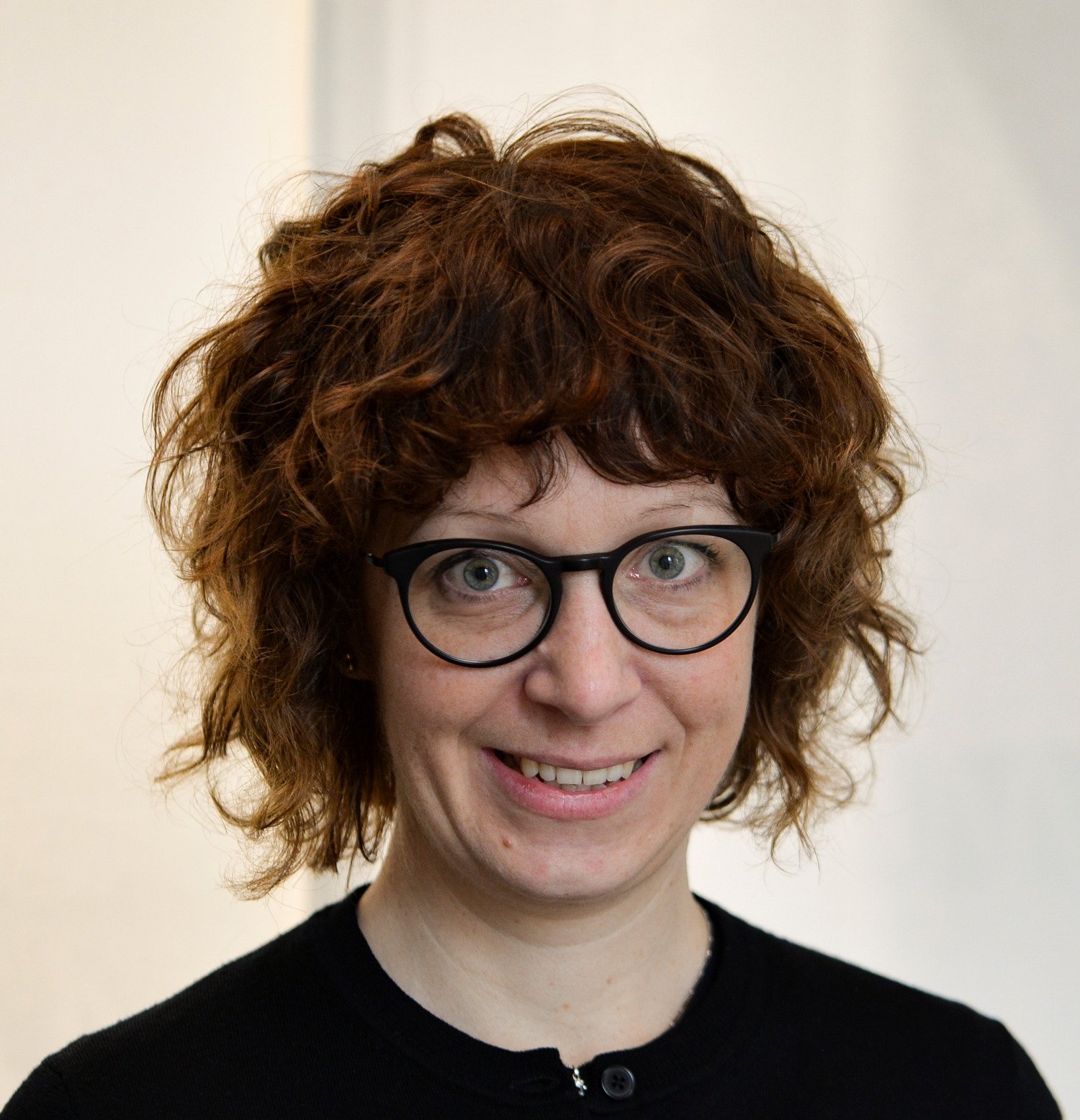 Profile photo of Hedvig Glans, a woman with short curly red hair and a black jumper