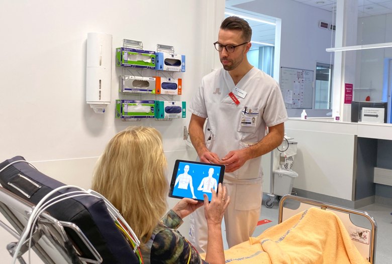 Photo of Helge Brandberg, advising a patient on how to use CLEOS.