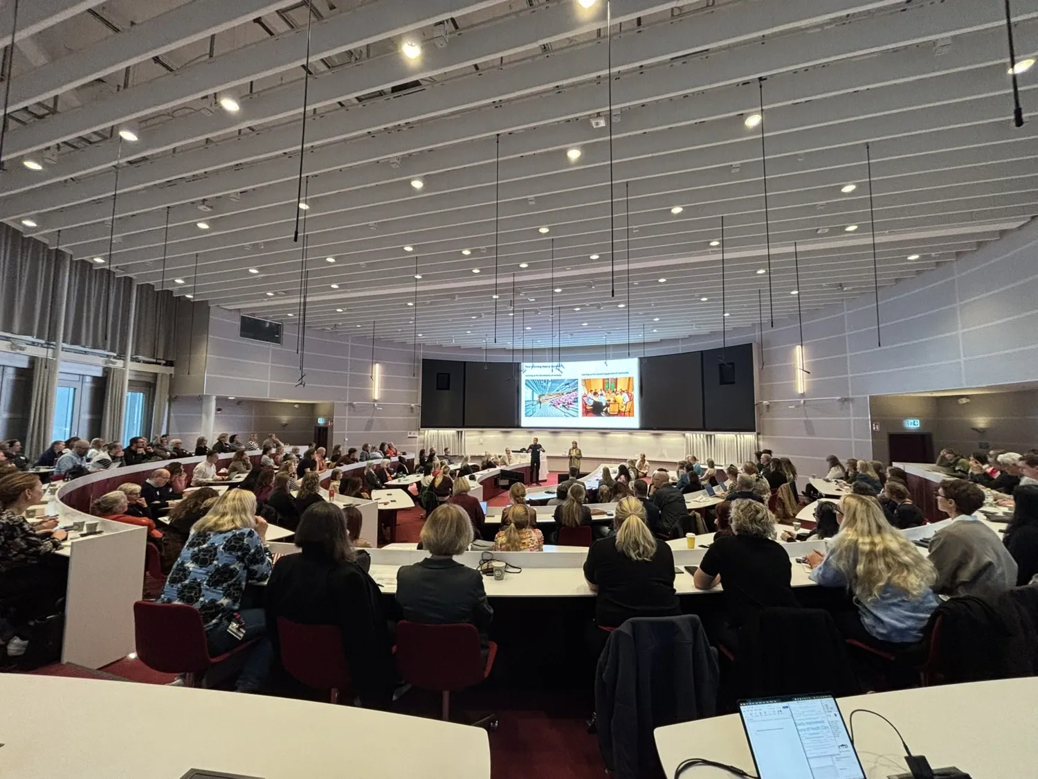 Room filled with people sitting down taken from behind.