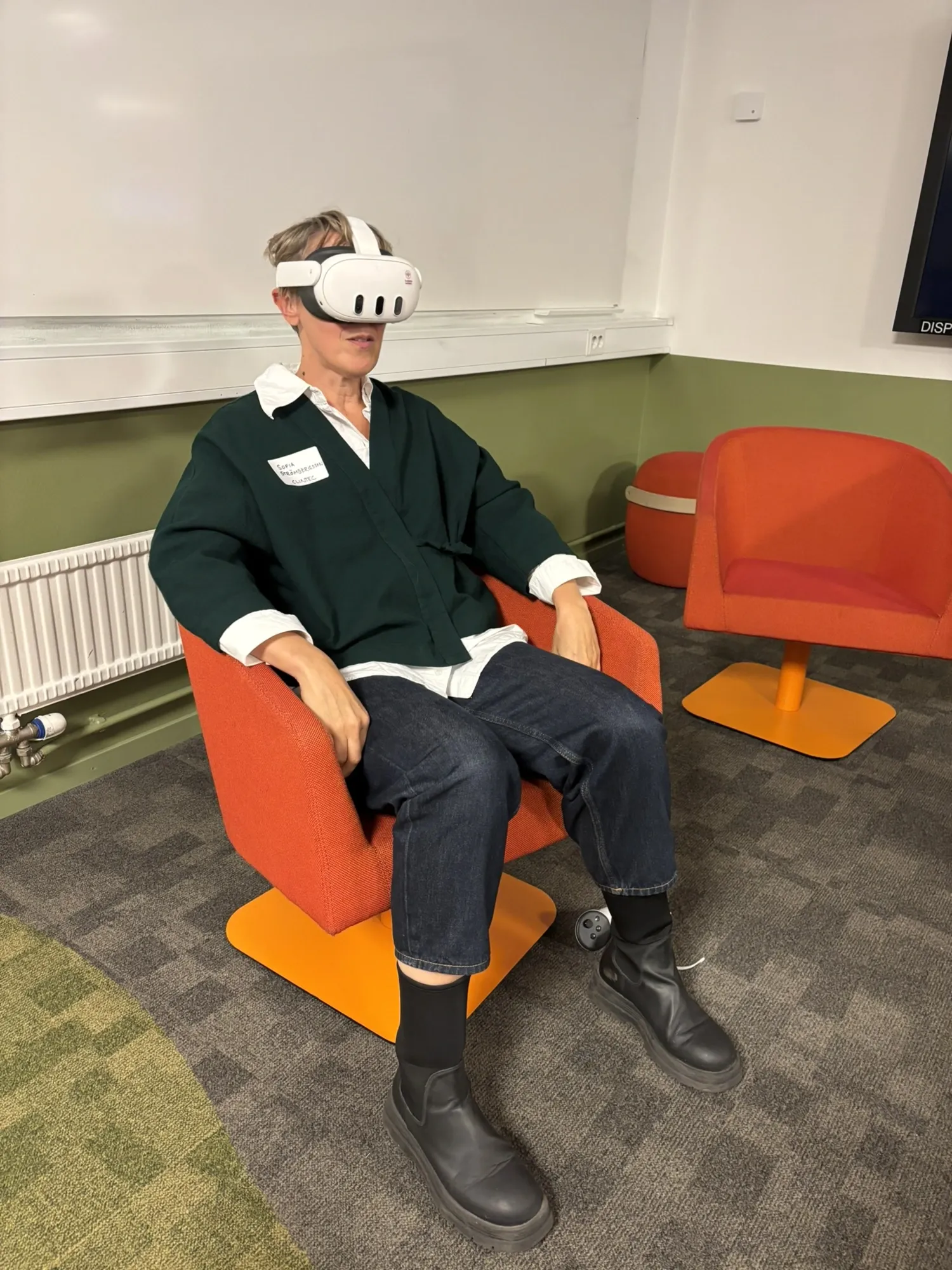 Sofia Strömbergsson sitts in an armchair with XR glasses on.
