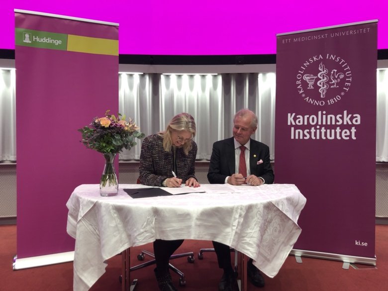 KI's President and Huddinge municipality’s Director sitting at a table, signing the agreement.