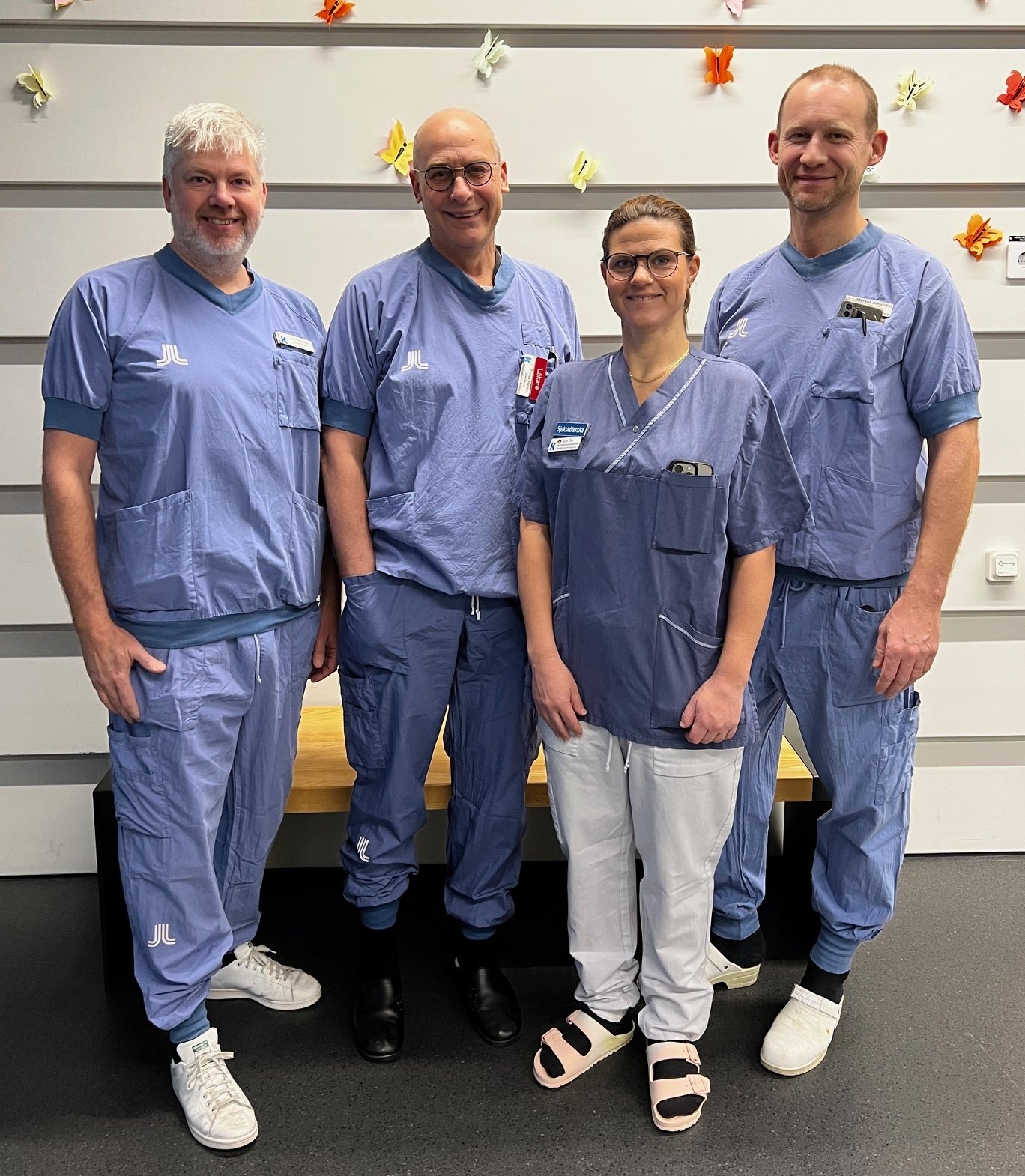 Four people in hospital scrubs. three men one woman