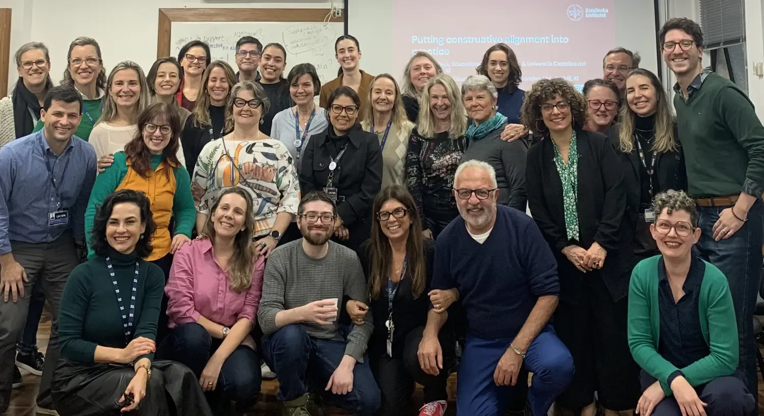 Large group of people standing and kneeling for a group photo in a classroom
