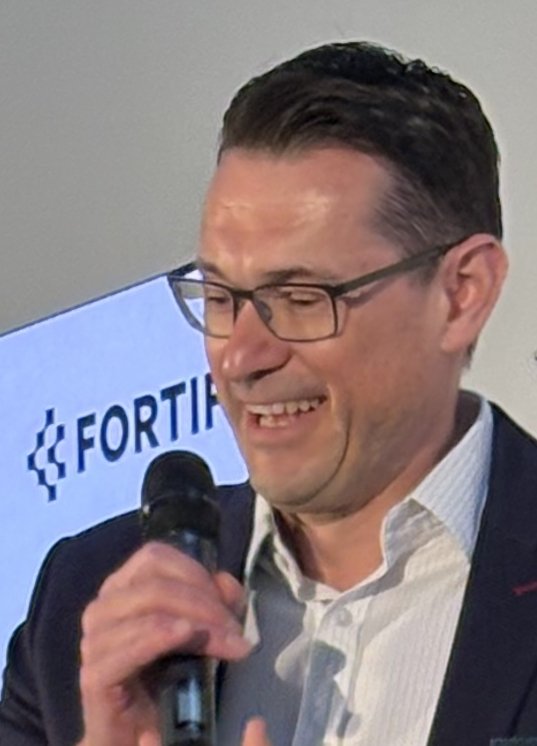 Two men standing on a podium during a conference. They are happy.