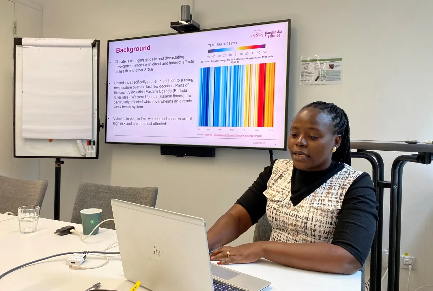 PhD student Irene Wanyana sitting by her laptop and presents her project on a screen.